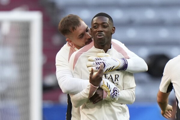 PSG's Ousmane Dembele, right, and PSG's goalkeeper Arnau Tenas talk during a training session ahead of the Champions League final soccer match between Paris Saint-Germain and Inter Milan in Munich, Germany, Friday, May 30, 2025. (AP Photo/Luca Bruno)