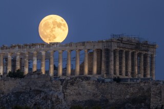 FILE - The moon rises in the sky behind the 5th century B.C. Parthenon temple at the ancient Acropolis hill, in Athens, July 31, 2023. The Parthenon Sculptures have been displayed in London for more than 200 years. But Greece vocally wants them back. Diplomacy failed when U.K. Prime Minister Rishi Sunak abruptly called off a London meeting scheduled for Tuesday Nov. 28, 2023 with Greek counterpart Kyriakos Mitsotakis. (AP Photo/Petros Giannakouris, File)