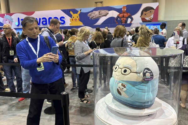 A person takes a photo of the Warren Buffett and Charlie Munger Squishmallows before Saturday's Berkshire Hathaway shareholders meeting in Omaha, Neb., on Friday, May 3, 2024. are again one of the hottest item for sale this year at the Berkshire Hathaway shareholders meeting. (AP Photo/Josh Funk)