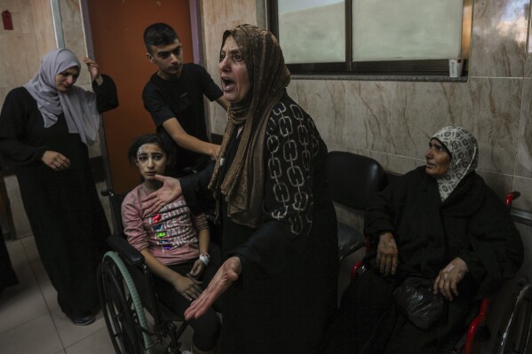At al-Aqsa Hospital in Deir el-Balah, central Gaza Strip, a Palestinian woman reacts next to the wounded during an Israeli airstrike, Sunday, Oct. 15, 2023. (AP Photo/Adel Hana)