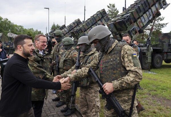 Ukraine's President Volodymyr Zelenskyy, left, and German Defence Minister Boris Pistorius, second left, greet German and Ukrainian soldiers during their visit to a military training area in the German state of Western Pomerania, Tuesday, June 11, 20242, to learn about the training of Ukrainian soldiers on the "Patriot" air defence missile system. (Jens Buettner/dpa via AP)
