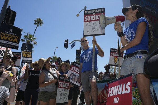 File - Actor and filmmaker Justine Bateman, right, speaks outside Netflix during a Writers Guild rally on July 13, 2023, in Los Angeles. Bateman said she was disturbed that AI models were "ingesting 100 years of film" and TV in a way that could destroy the structure of the film business and replace large portions of its labor pipeline. (AP Photo/Mark J. Terrill, File)