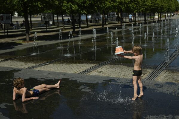 Children cool themselves by a fountain at Muzeon park in Moscow, Russia, Thursday, May 22, 2025. (AP Photo/Pavel Bednyakov)