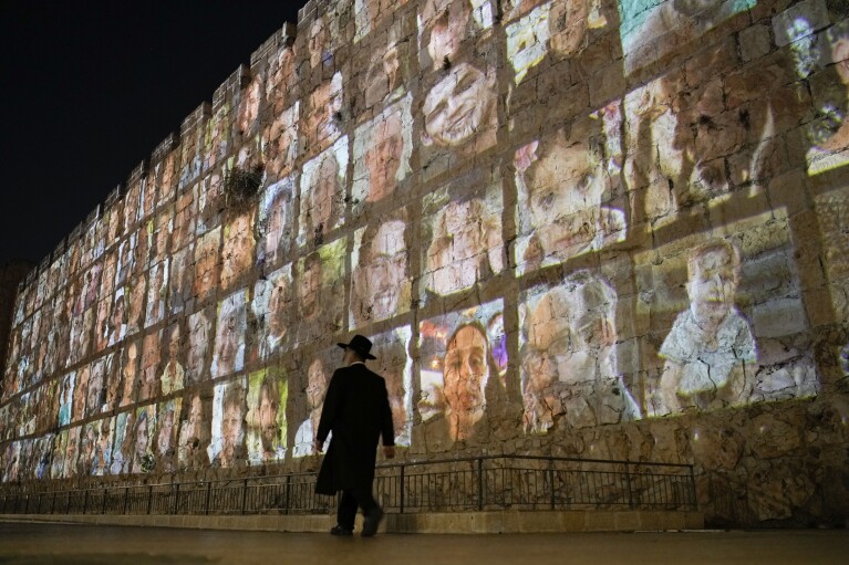 Photographs of Israeli hostages being held by Hamas militants are projected on the walls of Jerusalem's Old City, Monday, Nov. 6, 2023. The Islamic militant group killed 1,400 people and kidnapped 240 others in an unprecedented cross-border attack on Oct. 7, triggering a war that has raged for the past month. (AP Photo/Leo Correa)