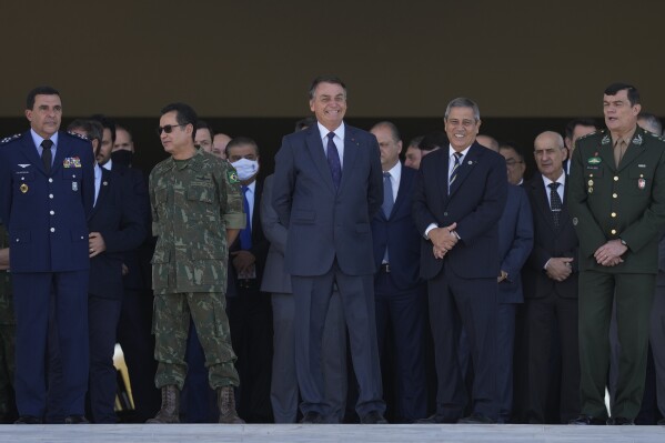 FILE - Brazilian President Jair Bolsonaro, center, and his Defense Minister Walter Braga Netto, second from right, watch a military convoy pass Planalto presidential palace, alongside military officials in Brasilia, Brazil, Tuesday, Aug. 10, 2021. Brazil’s Supreme Court unanimously voted Monday, April 8, 2024, that the armed forces have no constitutional power to intervene in disputes between government branches, marking a largely symbolic decision aimed at bolstering democracy after years of increasing threat of military intervention. (AP Photo/Eraldo Peres, File)