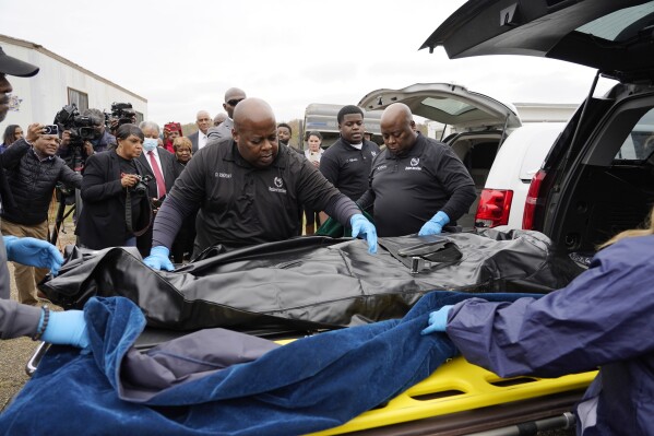 FILE - Westhaven Memorial Funeral Home staff adjust the body bag with the remains of Dexter Wade, who died after being hit by a Jackson, Miss., police SUV driven by an off-duty officer, in Raymond, Miss., Nov. 13, 2023. A third family says they recently discovered a relative was buried in a Mississippi pauper’s cemetery without their knowledge. Civil rights attorney Ben Crump says it is the latest case in which families learned the whereabouts of a deceased loved one from news reports instead of from officials in Hinds County, Mississippi. Crump says Jonathan David Hankins is the third person to have been quietly buried in the paupers’ cemetery near the Hinds County Penal Farm in the Jackson suburb of Raymond. (AP Photo/Rogelio V. Solis, file)