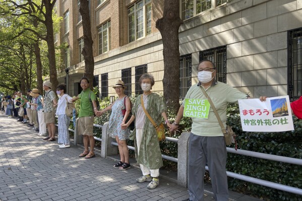 People form a human chain outside of the Ministry of Education, Culture, Sports, Science and Technology on Sunday, Sept. 17, 2023, demanding it scrap a controversial redevelopment of Tokyo’s beloved Jingu Gaien park area, part of whose land is owned by an independent sports promotion unit overseen by the ministry, in Tokyo, Japan.(AP Photo/Mari Yamaguchi)