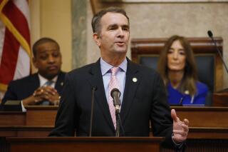 FILE - In this Jan. 8, 2020, file photo, Virginia Gov. Ralph Northam, center, gestures as he delivers his State of the Commonwealth address as House Speaker Eileen Filler-Corn, D-Fairfax, right, and Lt. Gov. Justin Fairfax, left, listen before a joint session of the Virginia Assembly at the state Capitol in Richmond, Va. Northam plans to declare a temporary emergency Wednesday, Jan. 15, banning all weapons, including guns, from Capitol Square ahead of a massive rally planned next week over gun rights. (AP Photo/Steve Helber, File)