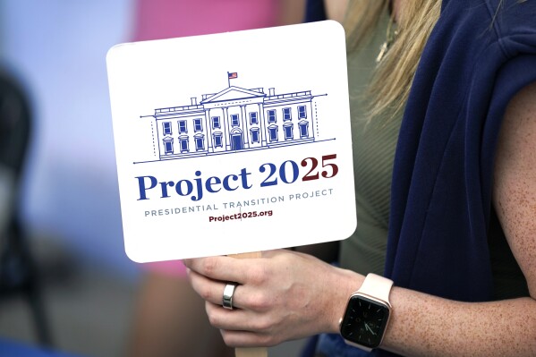 FILE - Kristen Eichamer holds a Project 2025 fan in the group's tent at the Iowa State Fair, Aug. 14, 2023, in Des Moines, Iowa. (AP Photo/Charlie Neibergall, File)