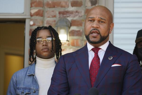 CORRECTS SPELLING OF FIRST NAME TO D’MONTERRIO - FedEx driver D'Monterrio Gibson, left, stands next to his attorney, Carlos Moore, during a news conference in Ridgeland, Miss., Thursday, Feb. 10, 2022. Gibson and his attorneys say the delivery driver was shot at and chased by a white father and son in Brookhaven while making deliveries, and that both suspects have been "undercharged" and call upon the authorities to instead charge the pair with attempted murder and hate crimes. (AP Photo/Rogelio V. Solis)