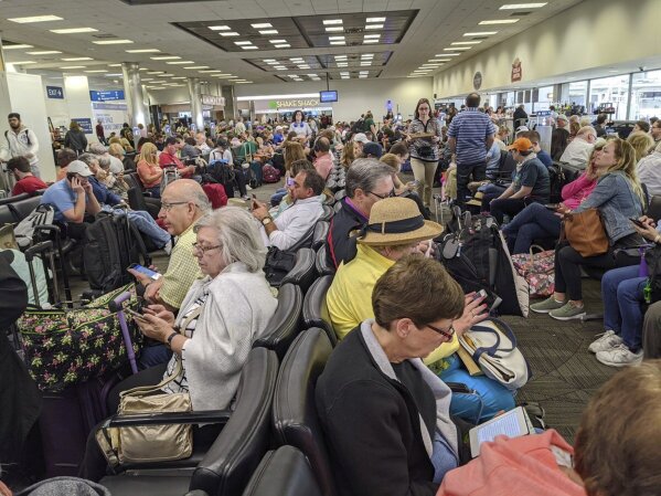 A gate area at Fort Lauderdale-Hollywood International Airport is crowded with travelers awaiting Delta flight 1420 to Atlanta, Saturday, March 14, 2020, in Fort Lauderdale, Fla. Weary travelers returning to the U.S. amid coronavirus-related travel restrictions are being greeted by long lines and hourslong waits for required medical screenings at airports. (John Scalzi via AP)
