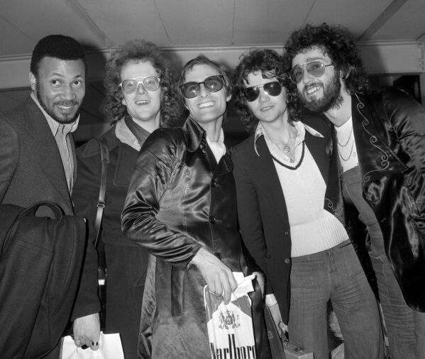 FILE - Steve Harley, center, and Cockney Rebel at London's Heathrow airport, Feb. 26, 1975, on their arrival from America. British musician Steve Harley, whose band Cockney Rebel had a huge hit with the song “Make Me Smile (Come Up and See Me),” has died. He was 73. Harley’s family said Sunday March 17, 2024 he had “passed away peacefully at home, with his family by his side.” (PA via AP)