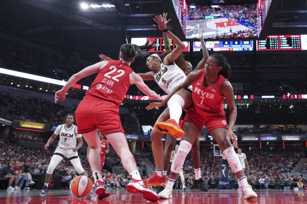 Indiana Fever guard Caitlin Clark, left, battles for the ball with Chicago Sky forward Angel Reese, center, during the second half an WNBA basketball game in Indianapolis, Saturday, May 17, 2025. (AP Photo/AJ Mast)