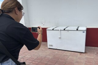 A Thai reporter takes a photo of an empty freezer at the Nong Prue police station in Pattaya, Chonburi province, Thailand, Tuesday, July 11, 2023. The dismembered body of a 62-year-old German businessman Hans-Peter Mack who has been missing for a week has been found in the freezer of a house in southern Thailand, police said Tuesday. (AP Photo)