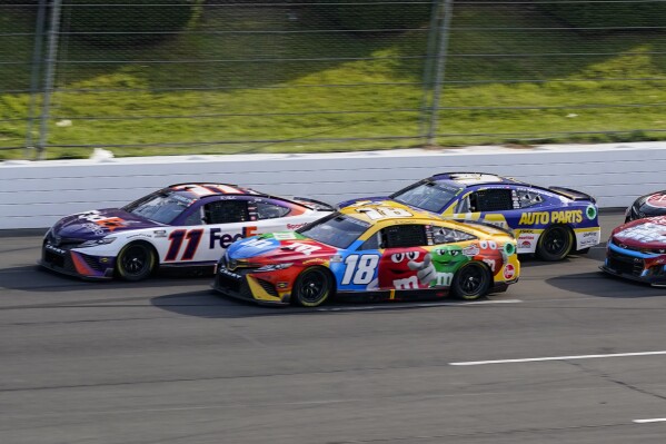 FILE - Denny Hamlin (11) and Kyle Busch (18) lead Chase Elliott (9), right, on a restart late in the NASCAR Cup Series auto race at Pocono Raceway, with Sunday, July 24, 2022, in Long Pond, Pa. Hamlin and Busch return to Pocono Raceway a year after they suffered disqualifications and had their 1-2 finishes thrown out. (AP Photo/Matt Slocum, File)
