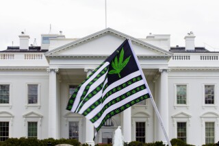 FILE - A demonstrator waves a flag with marijuana leaves depicted on it during a protest calling for the legalization of marijuana, outside of the White House on April 2, 2016, in Washington. President Joe Biden is pardoning thousands of people who were convicted of use and simple possession of marijuana on federal lands and in the District of Columbia. The White House says his action Friday is his latest round of executive clemencies meant to rectify racial disparities in the justice system. (AP Photo/Jose Luis Magana, File)