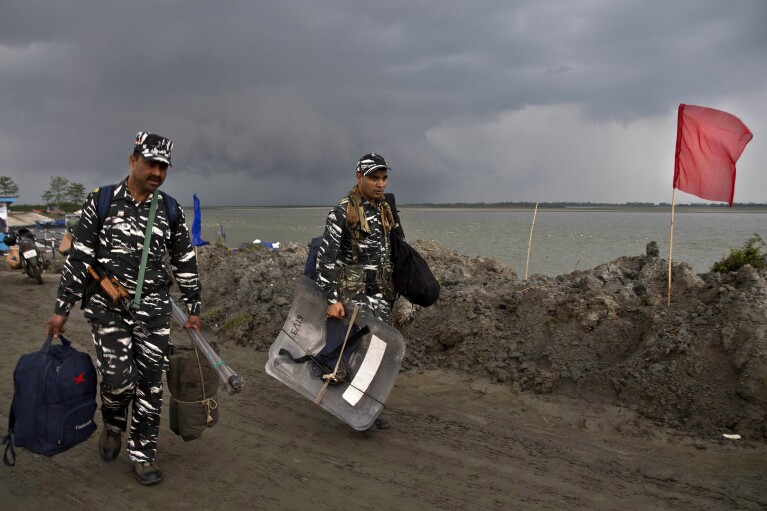 FILE-Indian paramilitary soldiers carry their luggage after disembarking from a ferry through the river Brahmaputra ahead of first phase of elections at Nimati Ghat in Jorhat, Assam, India, Tuesday, April 9, 2019. From April 19 to June 1, nearly 970 million Indians - or over 10% of the world’s population - will vote in the country's general elections. The mammoth electoral exercise is the biggest anywhere in the world - and will take 44 days to complete before results are announced on June 4. (AP Photo/Anupam Nath,File)