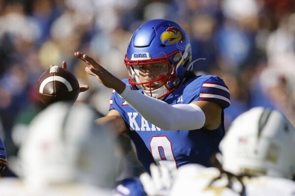 Kansas quarterback Jason Bean catches a snap during the first half of an NCAA college football game against Central Florida, Saturday, Oct. 7, 2023, in Lawrence, Kan. (AP Photo/Colin E. Braley)