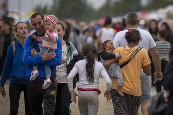 People walk by stands at a fair in Hagioaica, Romania, Saturday, Sept. 16, 2023. For many families in poorer areas of the country, Romania's autumn fairs, like the Titu Fair, are one of the very few still affordable entertainment events of the year. (AP Photo/Andreea Alexandru)