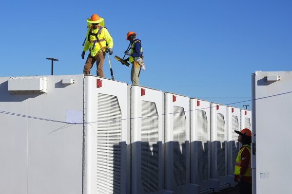 Workers do checks on battery storage pods at Orsted's Eleven Mile Solar Center lithium-ion battery storage energy facility Thursday, Feb. 29, 2024, in Coolidge, Ariz. Batteries allow renewables to replace fossil fuels like oil, gas and coal, while keeping a steady flow of power when sources like wind and solar are not producing. (AP Photo/Ross D. Franklin)