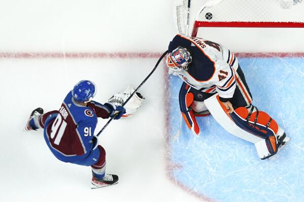 Edmonton Oilers goaltender Mike Smith (41) gives up a goal to Colorado Avalanche center Nathan MacKinnon as Nazem Kadri (91) watches during the third period in Game 2 of the NHL hockey Stanley Cup playoffs Western Conference finals Thursday, June 2, 2022, in Denver. (AP Photo/Jack Dempsey)