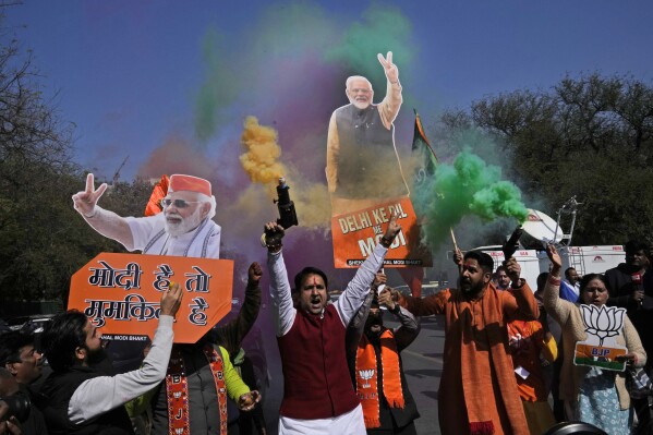 Supporters of Bharatiya Janata Party carrying cut outs of Indian Prime Minister Narendra Modi celebrate party's early leads as votes are being counted in the Delhi state election in New Delhi,India, Saturday, Feb. 8, 2025. (AP Photo/Manish Swarup)
