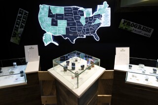 FILE - A map of cannabis legalization in the U.S. glows behind flower displays at the Empire Cannabis Club, Nov. 16, 2022, in New York. An advisory board approved on Tuesday, Feb. 13, 2024 a list of proposed rules and regulations that would govern the recreational use of cannabis in the U.S. Virgin Islands. (AP Photo/Julia Nikhinson, File)