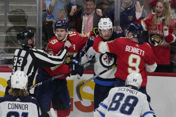 Florida Panthers center Sam Bennett (9) and Winnipeg Jets defenseman Dylan Samberg (54) fight as Florida Panthers left wing Matthew Tkachuk (19) is restrained by linesman Kilian McNamara (93), during the second period of an NHL hockey game, Friday, Nov. 24, 2023, in Sunrise, Fla. (AP Photo/Marta Lavandier)