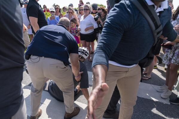 2022年6月18日土曜日、デラウェア州レホボスビーチにあるゴードンズ池の小道で、群衆に挨拶するために自転車から降りようとして転倒し、米国秘密情報局の職員に助けられるジョー・バイデン大統領。(AP写真/Manuel Balce Ceneta) )