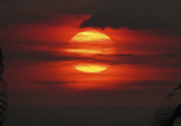 
              In this May 23, 2018, photo provided by Chris Stewart the sun sets through “vog,” or volcanic smog, in Kailua-Kona, Hawaii. Kilauea volcano on Hawaii’s Big Island has had it all over the past three weeks: molten rock shooting toward the sky, lava oozing from the ground and ash clouds rising miles into the air. You can also add "vog" to the mix. Retired photojournalist Chris Stewart says there’s one good thing about vog: It intensifies the colors of a sunset. But it depends on how thick the haze is. “Some days it’s thin enough you can see the sun passing through,” he said. “But other days we just go inside because we can’t see it at all.” (Chris Stewart via AP)
            