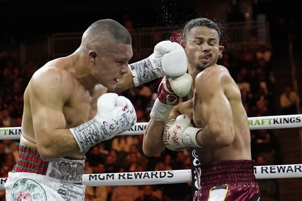 Isaac Cruz, of Mexico, hits Rolando Romero in a super lightweight title bout Saturday, March 30, 2024, in Las Vegas. (AP Photo/John Locher)