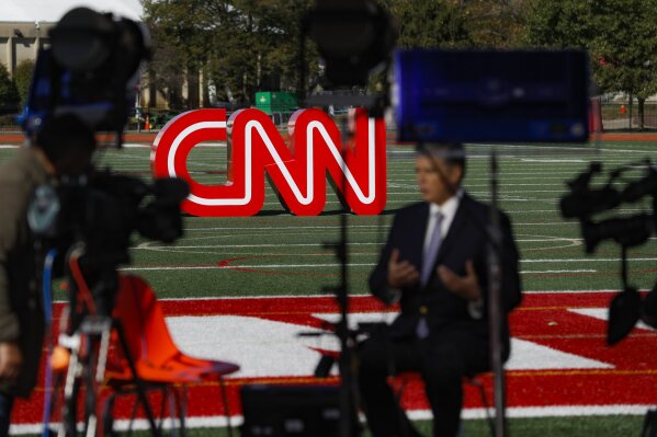 A journalist records video near a CNN sign on an athletic field outside the Clements Recreation Center where the CNN/New York Times will host the Democratic presidential primary debate at Otterbein University, Monday, Oct. 14, 2019, in Westerville, Ohio. (AP Photo/John Minchillo)