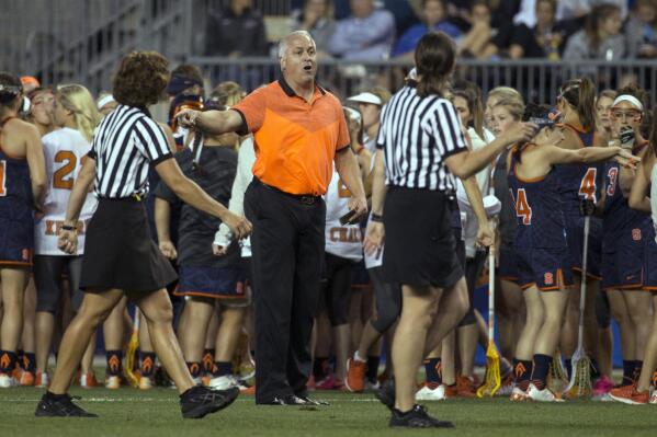 FILE - In this Friday, May 22, 2015, file photo, Syracuse head coach Gary Gait, center, talks with he officials during the first half of the semifinals in the NCAA Division I women's lacrosse tournament against the Maryland, in Chester, Pa. Gait, who has coached the Syracuse women’s lacrosse team for the past 14 years and built the program into a national power, will succeed current men's coach John Desko, who announced his retirement Monday, June 7, 2021, after 22 seasons and five national championships. (AP Photo/Chris Szagola, File)
