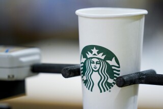 A single-use cup undergoes a rigidity test at the Tryer Center at Starbucks headquarters, Wednesday, June 28, 2023, in Seattle. Paper pulp from recycled cups has shorter fibers than virgin pulp, which means less rigidity, important particularly with hot coffee. Part of the company's goal is to cut waste, water use and carbon emissions in half by 2030. (AP Photo/Lindsey Wasson)