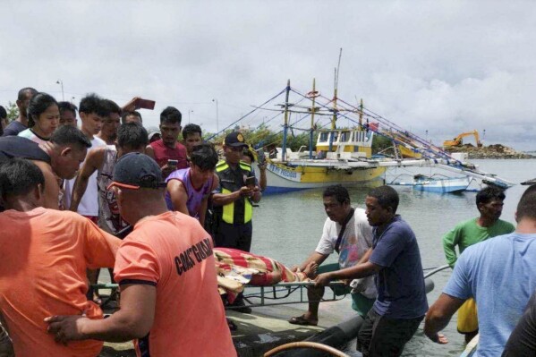 In this photo provided by the Philippine Coast Guard, rescuers carry the body of one of the victims as it arrives at a port in Infanta, Pangasinan province, Philippines on Tuesday Oct. 3, 2023. A few Filipino fishermen died in the disputed South China Sea after their boat was accidentally hit by a passing commercial vessel, the Philippine coast guard said Wednesday. (Philippine Coast Guard via AP)