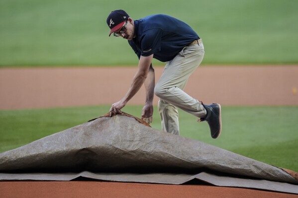 A ground crew member covers the mound before baseball game between the Atlanta Braves and the San Diego Padres, Saturday, May 18, 2024, in Atlanta. (AP Photo/Mike Stewart)