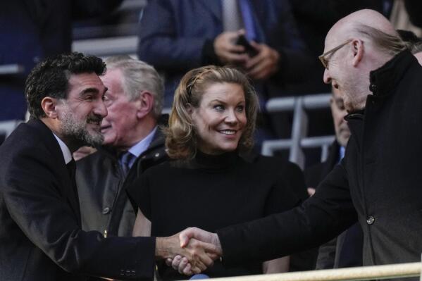 Manchester United's Chairman Avie Glazer, right, and Newcastle United's Chairman Yasir Al-Rumayyan, left, shake hands and Newcastle's Club Director Amanda Staveley, centre, smiles before English League Cup final soccer match between Manchester United and Newcastle United at Wembley Stadium in London, Sunday, Feb. 26, 2023. (AP Photo/Alastair Grant)