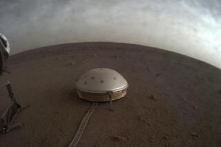 In this undated photo made available by NASA on Thursday, July 22, 2021, clouds drift over the dome-covered SEIS seismometer of the InSight lander on the surface of Mars. The quake-measuring device is providing the first detailed look at the red planet’s interior, revealing a surprisingly thin crust and a molten core. In a series of articles published in July 2021, scientists reported that the Martian crust is within the thickness range of Earth’s. Mars’ mantle, meanwhile, is roughly half that of our own much bigger planet, while the core _ measured from the dusty surface to dead center _ is more than 1,000 miles smaller. (NASA/JPL-Caltech via AP)