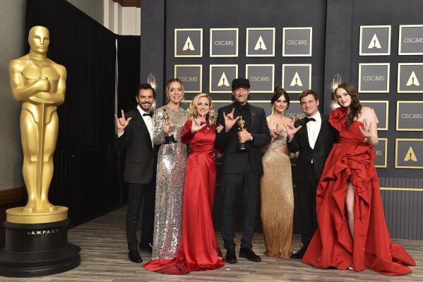FILE - Eugenio Derbez, from left, Sian Heder, Marlee Matlin, Troy Kotsur, Emilia Jones, Daniel Durant and Amy Forsyth, winners of the award for best picture for "CODA," pose in the press room while signing "I love you" at the Oscars on March 27, 2022, at the Dolby Theatre in Los Angeles. The three Oscar wins for the film “CODA” has provided an unprecedented feeling of affirmation to people in the Deaf community.  (Photo by Jordan Strauss/Invision/AP, File)