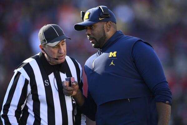 Michigan acting head coach Sherrone Moore, right, talks with an official during the second half of an NCAA college football game against Maryland, Saturday, Nov. 18, 2023, in College Park, Md. Michigan won 31-24. (AP Photo/Nick Wass)
