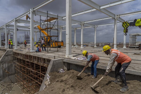 Employees work at the site of Adani Green Energy Limited's Renewable Energy Park in the salt desert of Karim Shahi village, near Khavda, Bhuj district near the India-Pakistan border in the western state of Gujarat, India, Thursday, Sept. 21, 2023. India is developing a 30 gigawatt hybrid — wind and solar — renewable energy project on one of the largest salt deserts in the world. (AP Photo/Rafiq Maqbool)