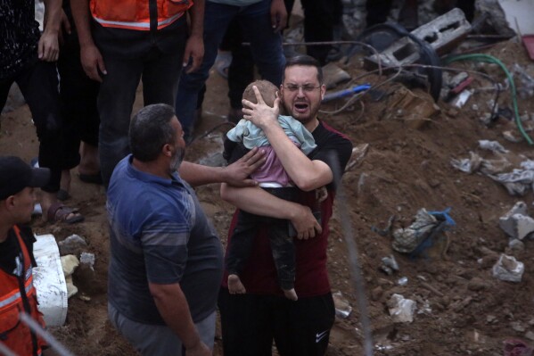 FILE - A Palestinian man cries while holding a dead child who was found under the rubble of a destroyed building following Israeli airstrikes in Nusseirat refugee camp, central Gaza Strip on Oct. 31, 2023. In just 25 days of war, more than 3,600 Palestinian children have been killed in Gaza, according to Gaza's Hamas-run Health Ministry. The advocacy group Save The Children says more children were killed in Gaza in October 2023 than in all conflict zones around the world combined in 2022. (AP Photo/Mohammed Dahman, File)