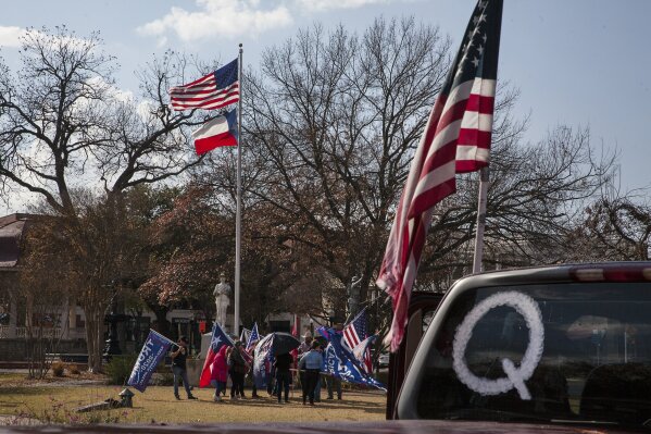 FILE - In this Jan. 6, 2021, file photo, a QAnon symbol is displayed on a car as New Braunfels Trump Train members meet in support of President Trump at the Main Plaza in New Braunfels, Texas.  Experts and former QAnon believers say they have tips for anyone wondering how to talk to people consumed by the conspiracy theory. (Mikala Compton/Herald-Zeitung via AP, File)