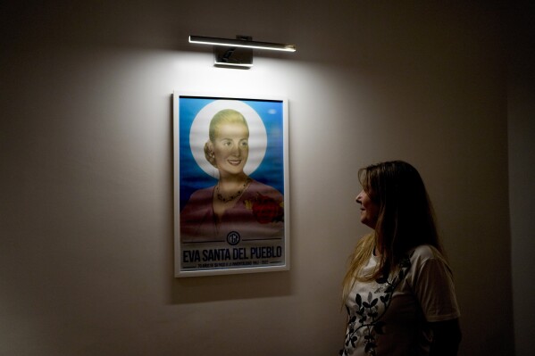 Angeles Celerier looks at a framed poster of Argentine former first lady María Eva Duarte de Perón, better known as Eva Perón, or Evita, titled "Saint Eva of the People", at a union headquarters' chapel, in Buenos Aires, Argentina, Wednesday, Jan. 24, 2024. (AP Photo/Natacha Pisarenko)