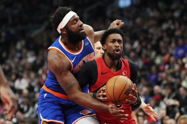 New York Knicks center Mitchell Robinson, left, and Toronto Raptors guard Kobi Simmons vie for the ball during the first half of an NBA basketball game Wednesday, March 27, 2024, in Toronto. (Frank Gunn/The Canadian Press via AP)