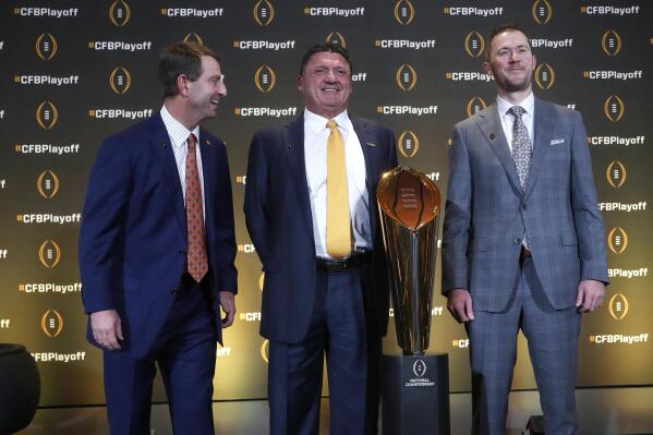 FILE - Clemson head coach Dabo Swinney, left, jokes with LSU head coach Ed Orgeron and Oklahoma head coach Lincoln Riley, right, as they pose with the College Football Championship trophy during a news conference ahead for the College Football playoffs in Atlanta, in this Thursday, Dec. 12, 2019, file photo. The College Football Playoff would expand from four to 12 teams, with six spots reserved for the highest ranked conference champions, under a proposal that will be considered next week by the league commissioners who manage the postseason system. A 12-team playoff would also include six at-large selections and no limit on how many teams can come from any one conference, a person familiar with announcement told The Associated Press on Thursday, June 10, 2021. The person spoke on condition of anonymity because the CFP has not yet released details. (AP Photo/John Bazemore, File)