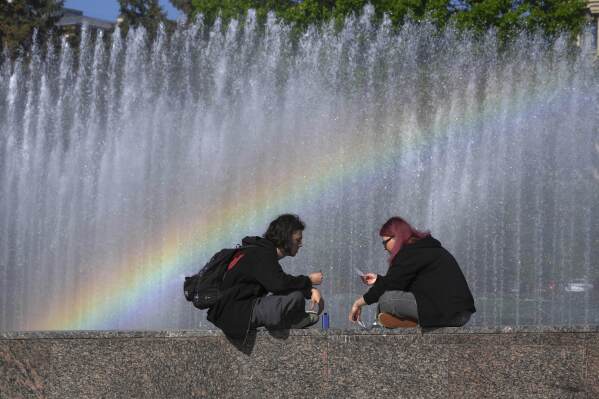 A couple play cards near a fountain in St. Petersburg, Russia, Tuesday, June 3, 2025. (AP Photo/Dmitri Lovetsky)