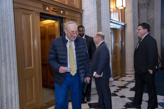 Senate Majority Leader Chuck Schumer, D-N.Y., walks to the chamber after speaking with Sen. Chris Coons, D-Del., right, as lawmakers rush to complete passage of a $1.7 trillion bill to fund the government before a midnight Friday deadline or face the prospect of a partial government shutdown going into the Christmas holiday, at the Capitol in Washington, Wednesday, Dec. 21, 2022. (AP Photo/J. Scott Applewhite)