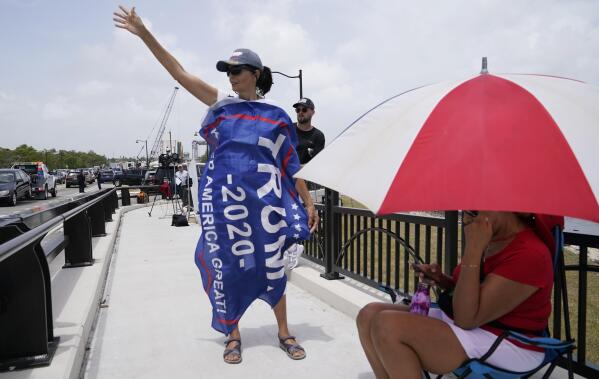 A Donald Trump supporter stands on a bridge outside the entrance to former President Donald Trump's Mar-a-Lago estate, Tuesday, Aug. 9, 2022, in Palm Beach, Fla. The FBI searched Trump's Mar-a-Lago estate as part of an investigation into whether he took classified records from the White House to his Florida residence, people familiar with the matter said Monday. (AP Photo/Lynne Sladky)