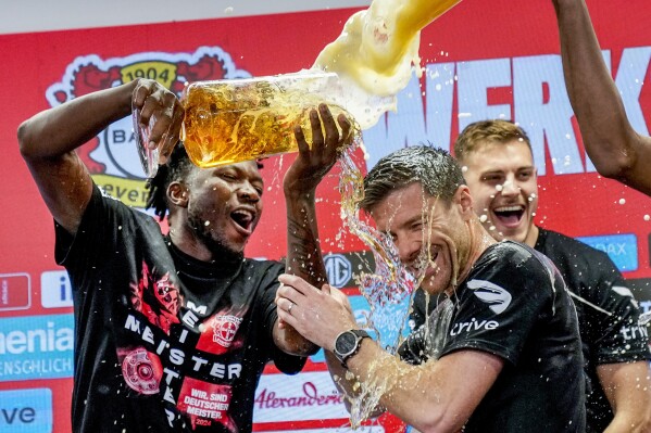 Leverkusen's head coach Xabi Alonso , centre, is sprayed with beer after Bayer Leverkusen won the German Bundesliga title beating Werder Bremen in Leverkusen, Germany, Sunday, April 14, 2024. (AP Photo/Martin Meissner)